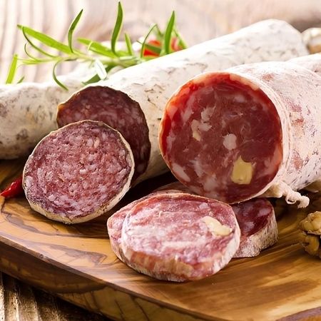 Auf einem Holzschneidebrett liegt in Scheiben geschnittene Salami